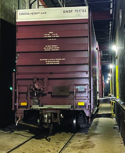 An excess-height BNSF railcar beside ELM’s warehouse loading dock