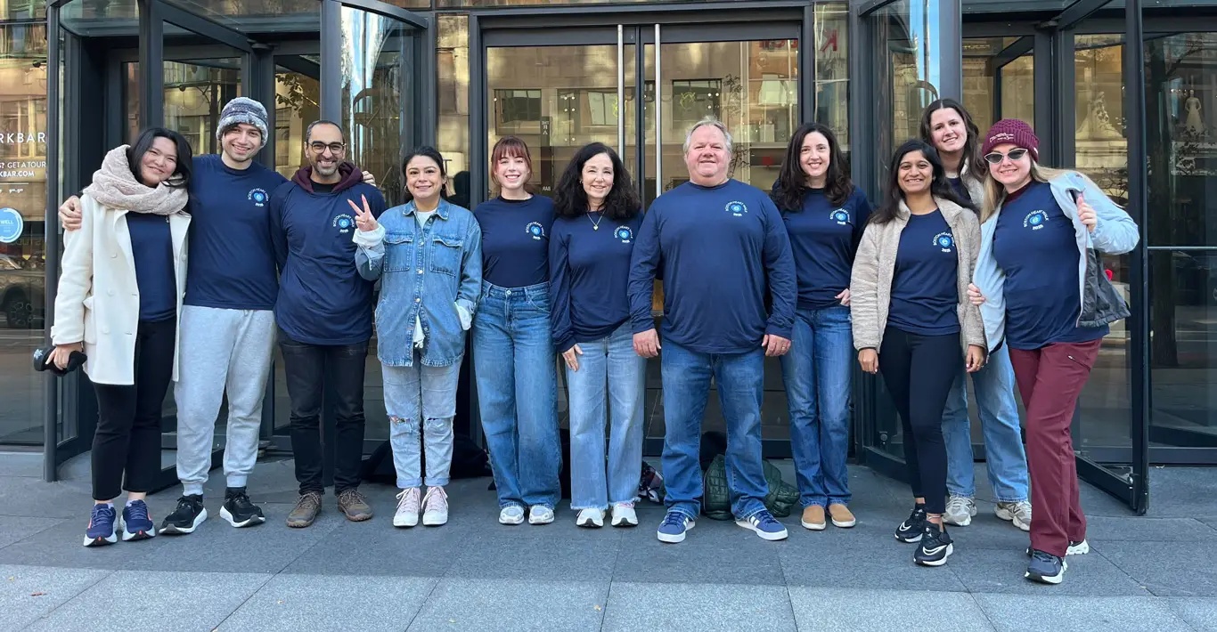 Elucid team members in matching blue shirts outside a glass building