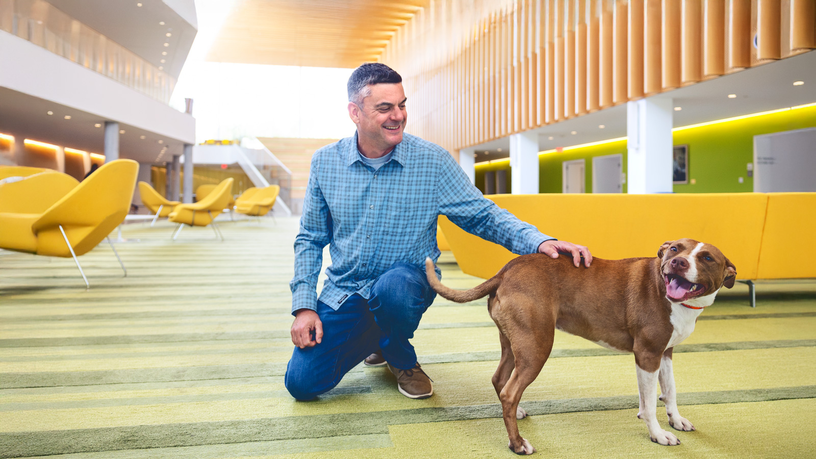 Embark co-founder Adam Boyko kneeling beside Nina in Cornell’s veterinary college