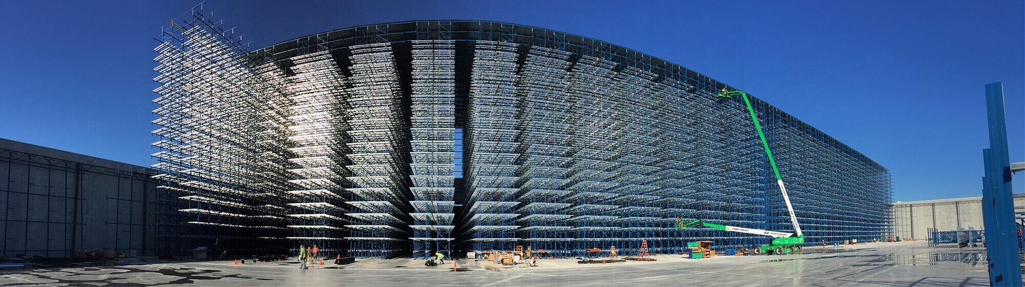 Large construction structure with dense steel framing, workers and elevated work platforms