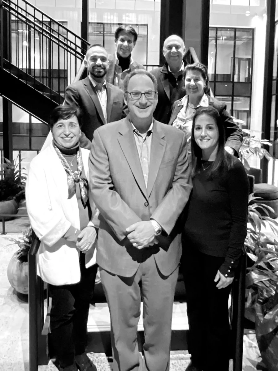 Members of the Emigrant Family Office team gathered beside an indoor staircase