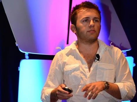 Emil Hajric speaking onstage, holding a presentation remote