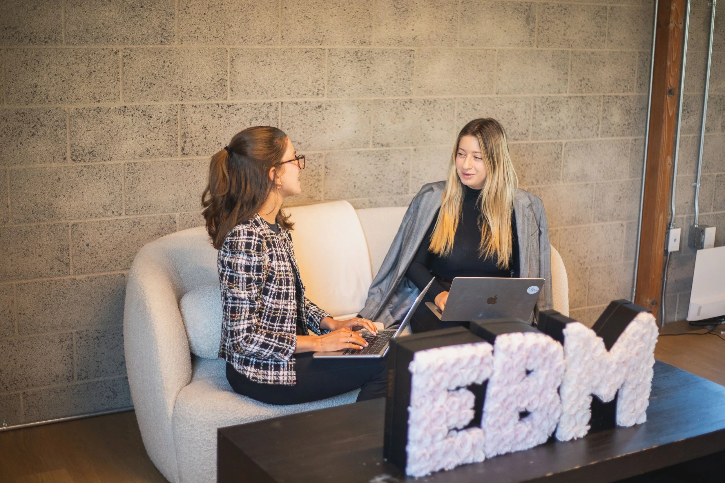 Emily Blair Marcus, right, talking with a colleague beside laptops in the Emily Blair Media office
