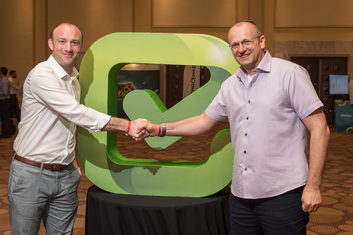 Emmanuel Benzaquen, left, and Maty Siman shaking hands beside a green Checkmarx symbol