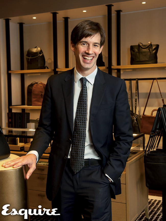 Emmanuel Ruelland standing beside a display of leather bags in a Coach store