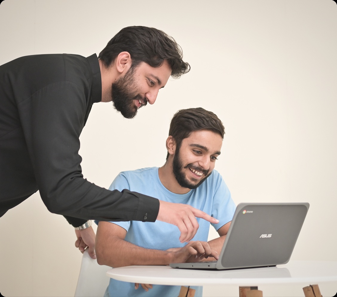 Two Emumba colleagues working together at a laptop in a mentorship photograph