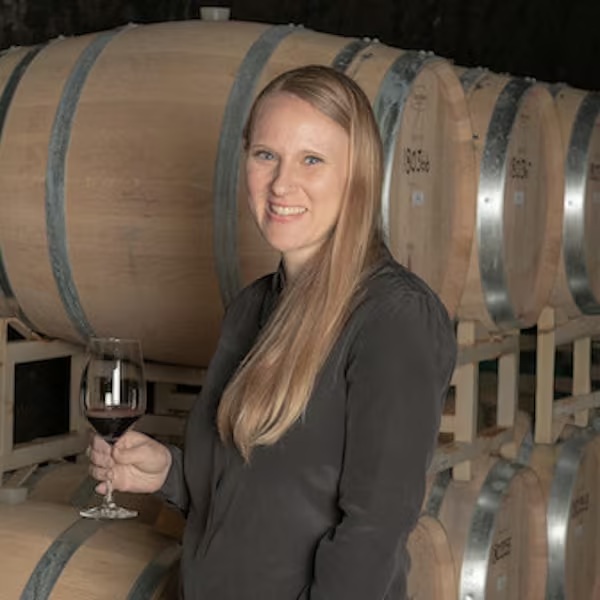 Antinori Napa Valley winemaker Marla Carroll holding a wine glass beside stacked barrels