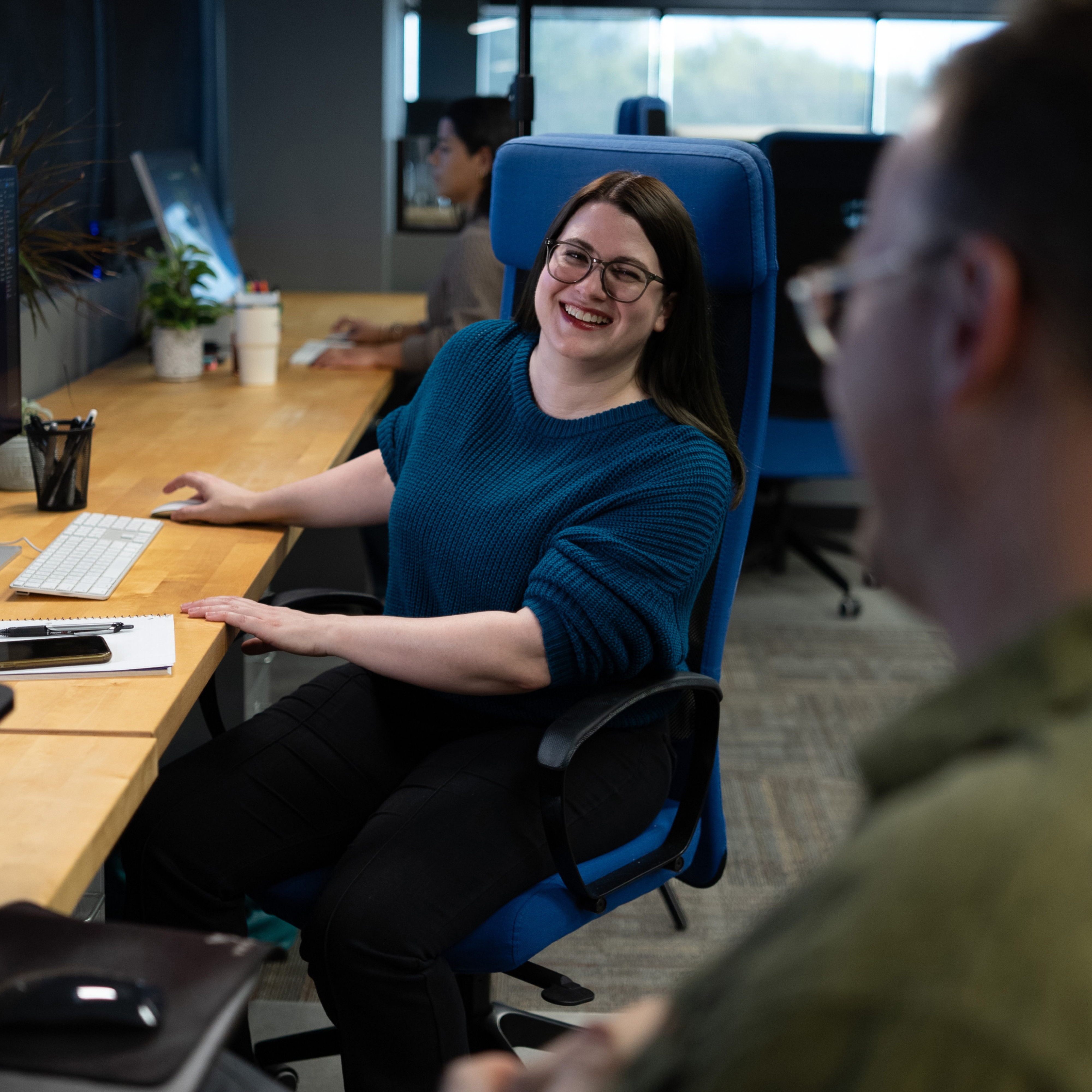 An Encore team member in the company's Longview office speaks with colleagues at her desk