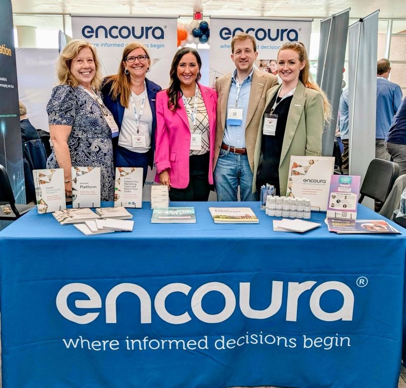 Five Encoura representatives standing behind their conference booth at NACCAP