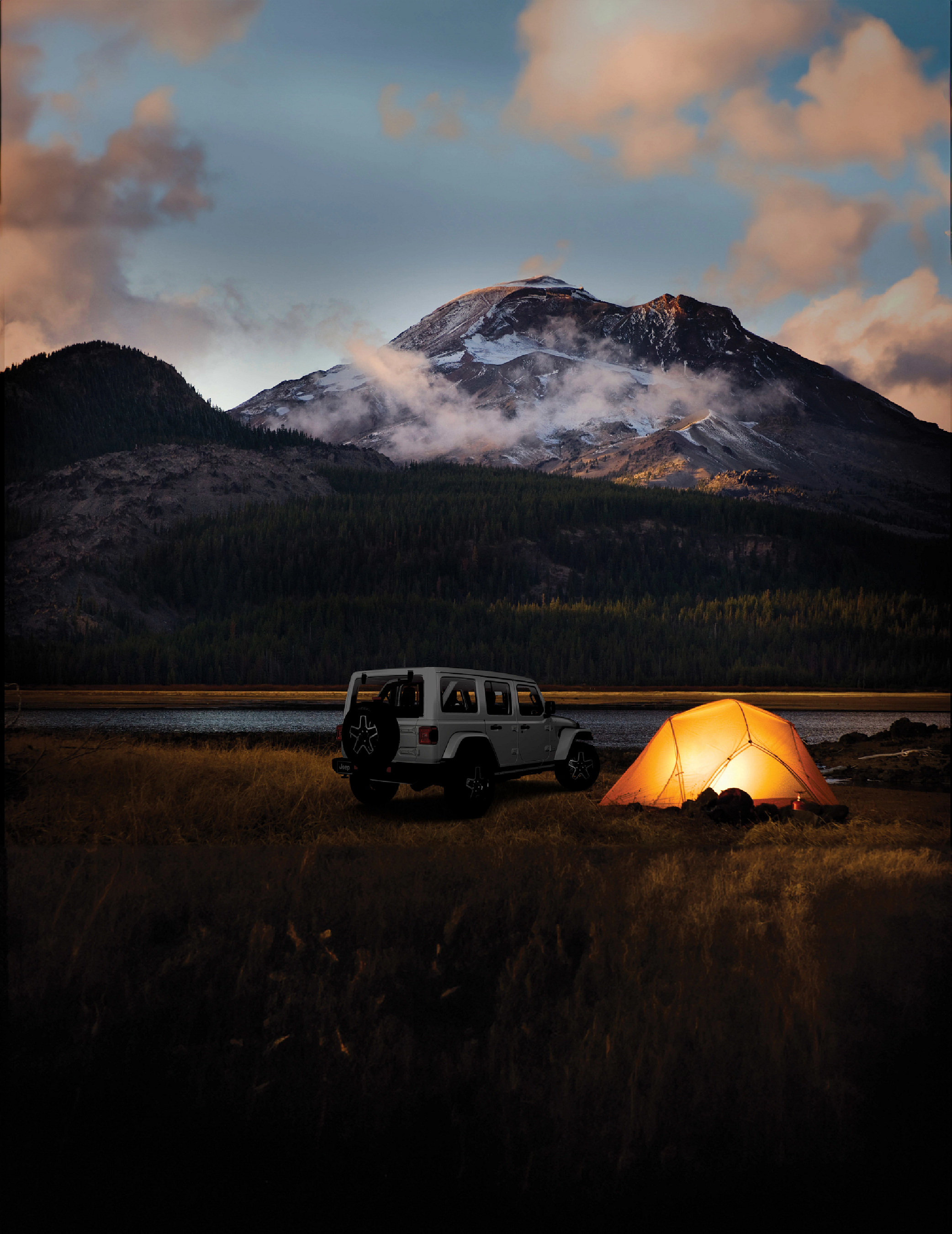Jeep beside an illuminated tent beneath a mountain at dusk, in the Jeep x Energizer campaign