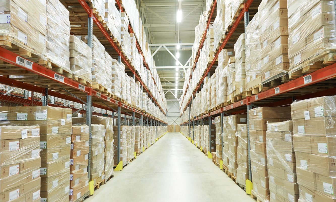Tall pallet racks lining a brightly lit warehouse aisle