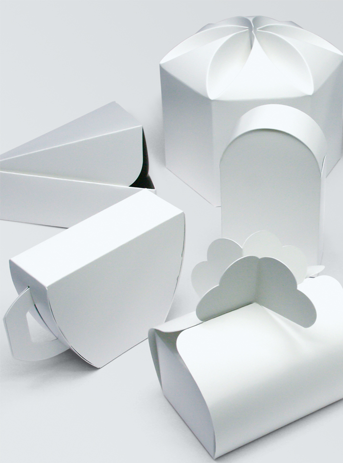 White paperboard packaging prototypes with curved lids, folded closures and rounded forms