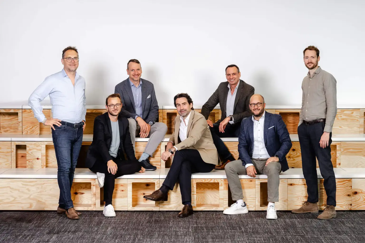 Christoph Bauer with the Entirely leadership team, posed on wooden seating