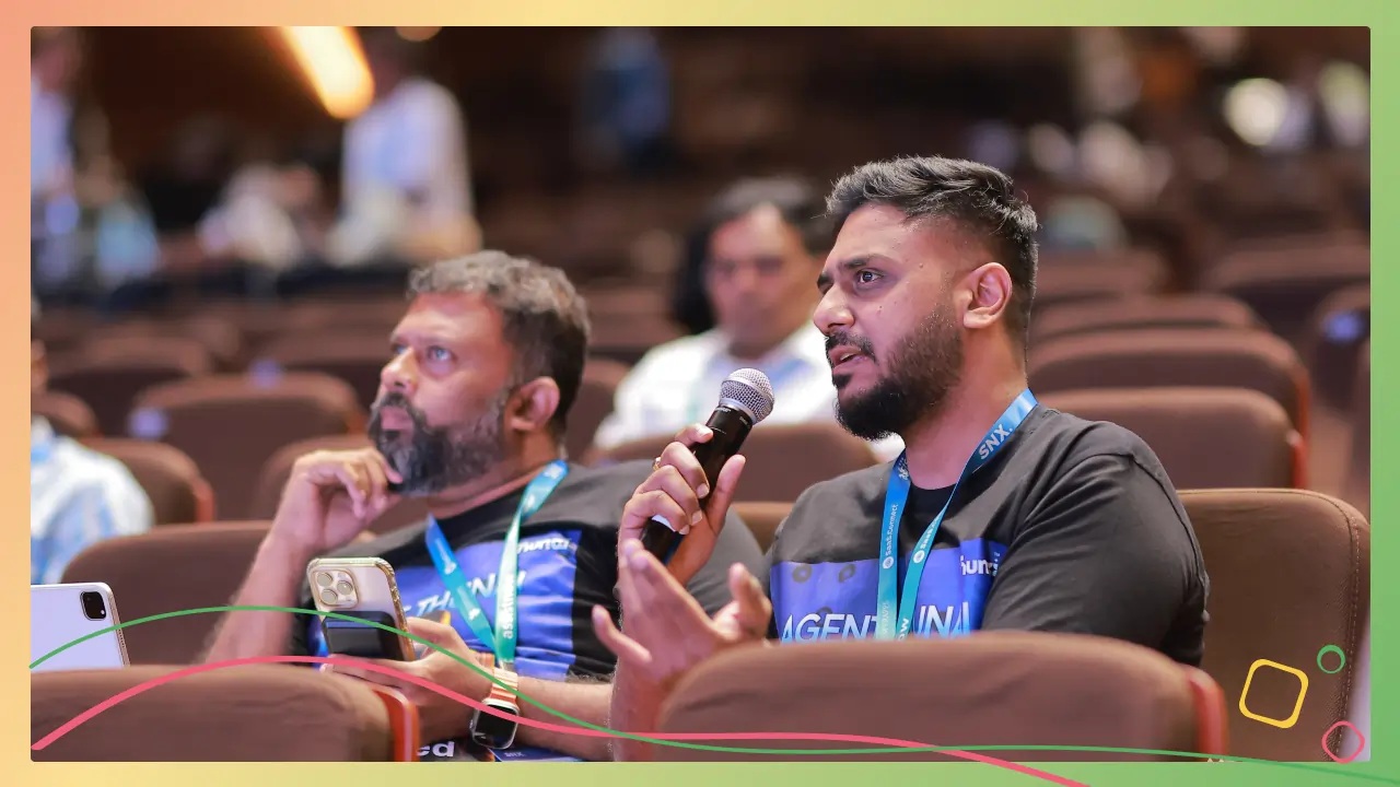 Participants wearing Thunai shirts at SaaS Connect, with one speaking into a handheld microphone