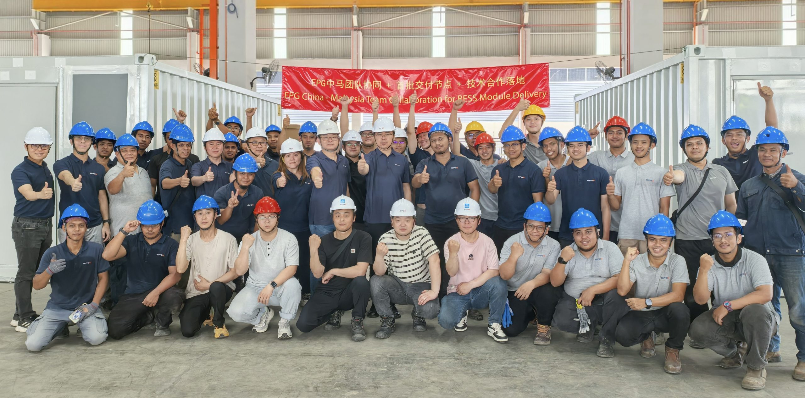 EPG Malaysia and China delivery teams in hard hats beside battery-storage modules at the manufacturing facility