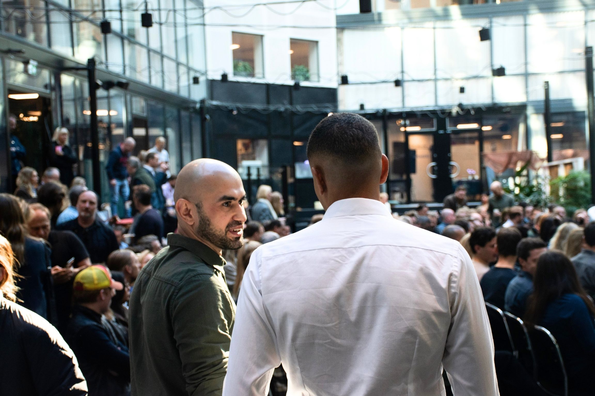 People talking during a crowded gathering in Epicenter’s glass-roofed atrium