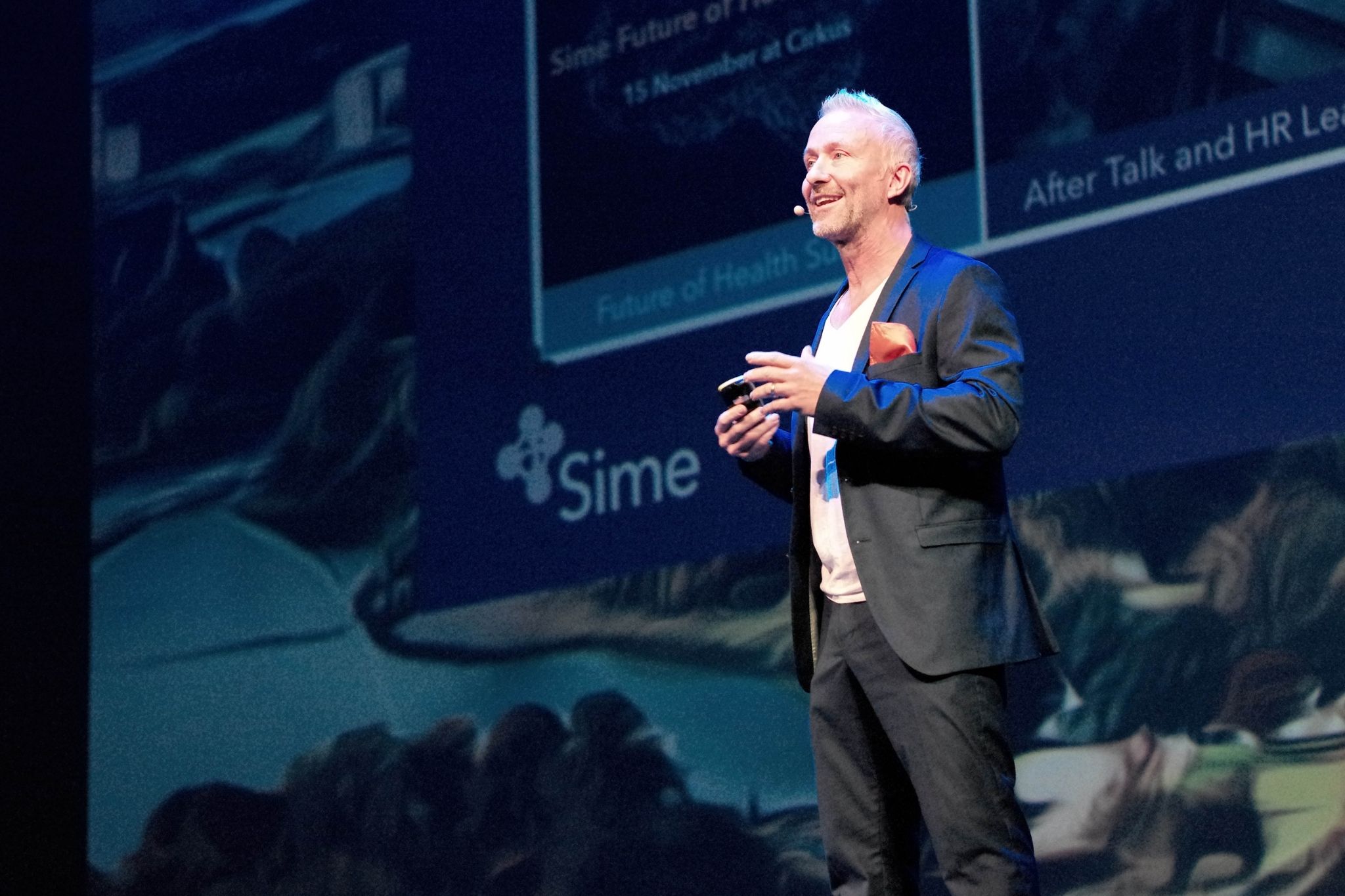 A speaker with a headset microphone presenting on a SIME stage