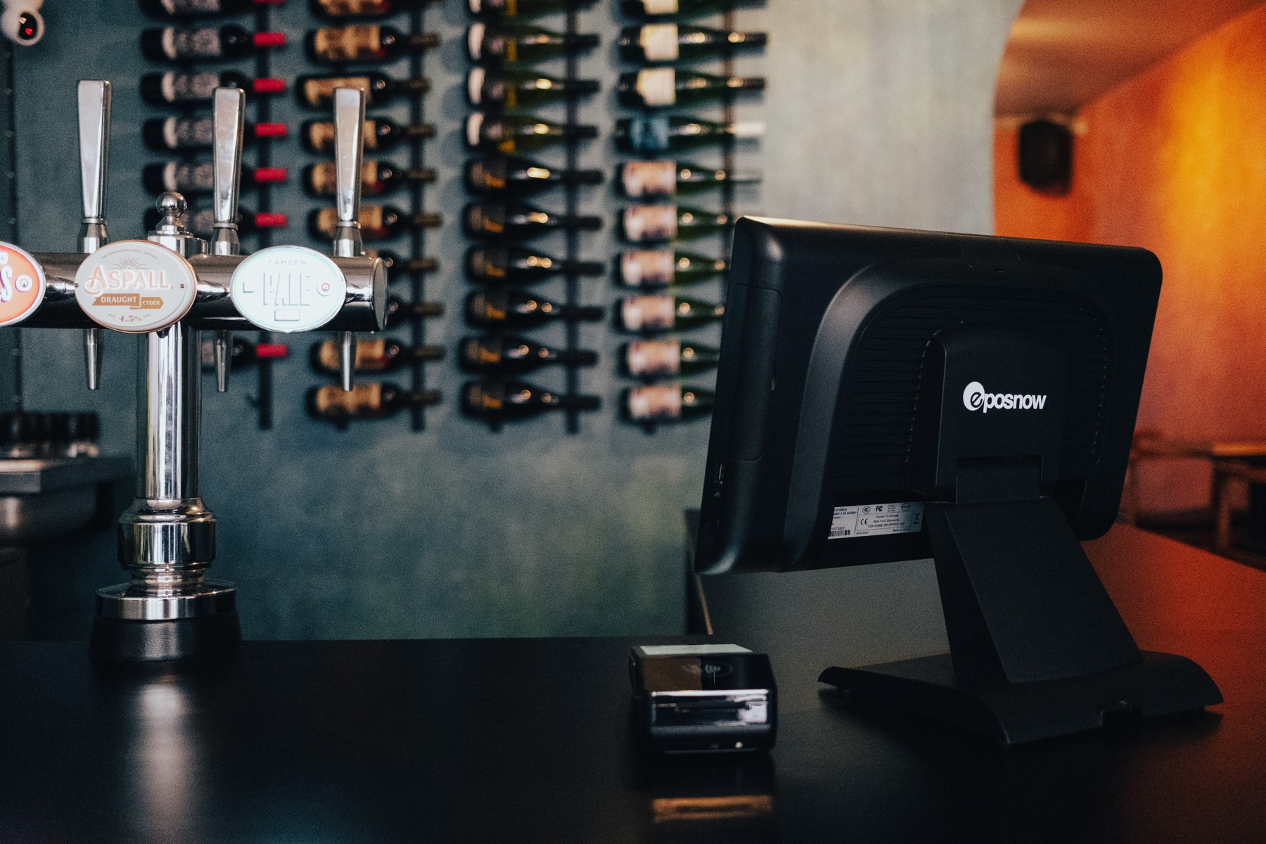 Epos Now terminal beside draught taps and a wall of bottles