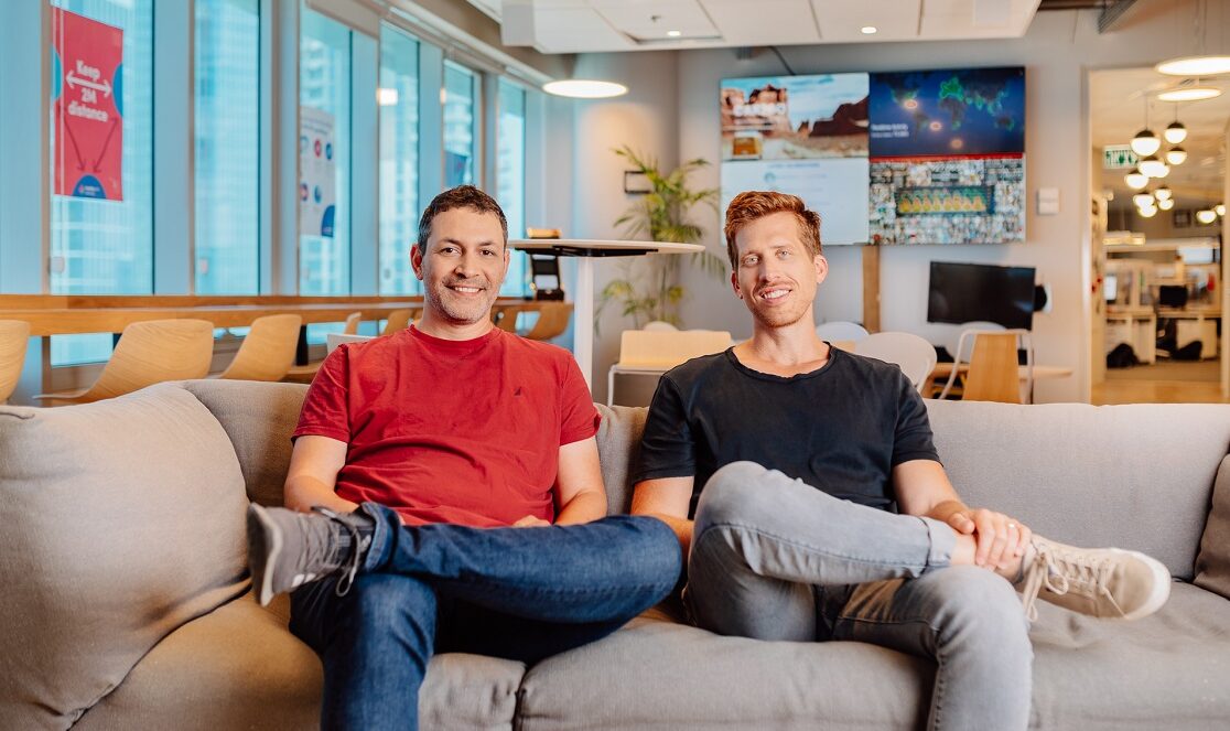 Roy Mann and Eran Zinman seated together on a sofa in the monday.com office