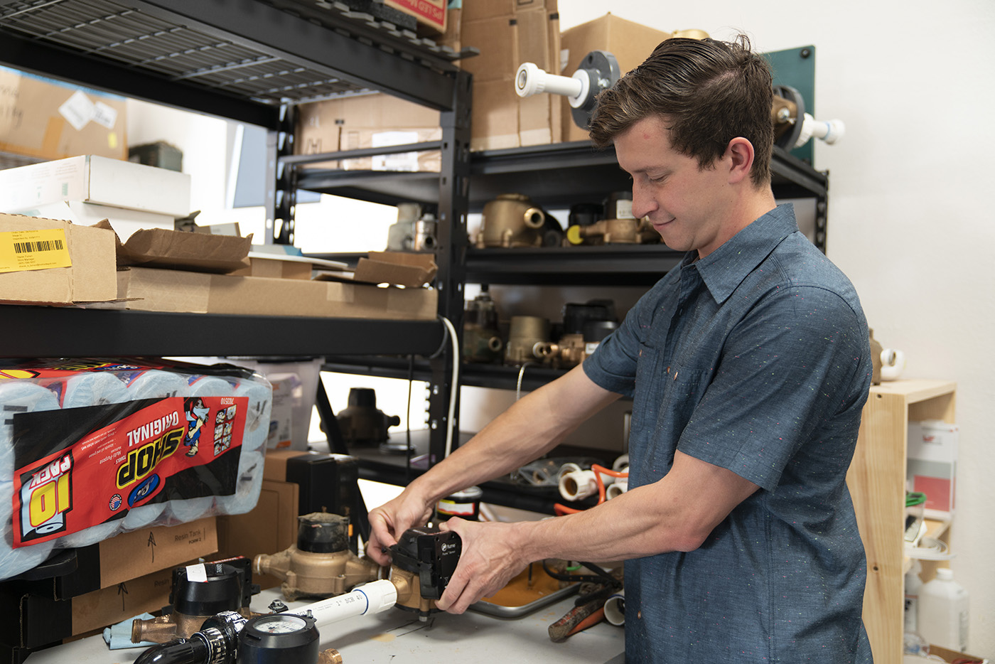 Eric Adler works with a Flume sensor and water-meter testing equipment in a workshop