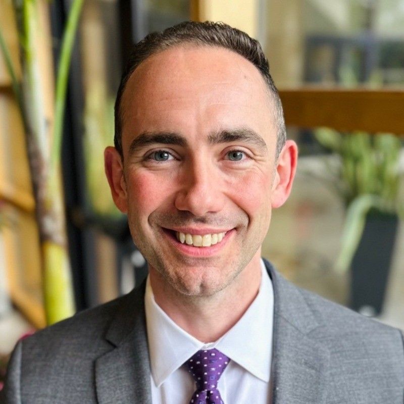 Eric Clements in a suit, photographed in an office setting