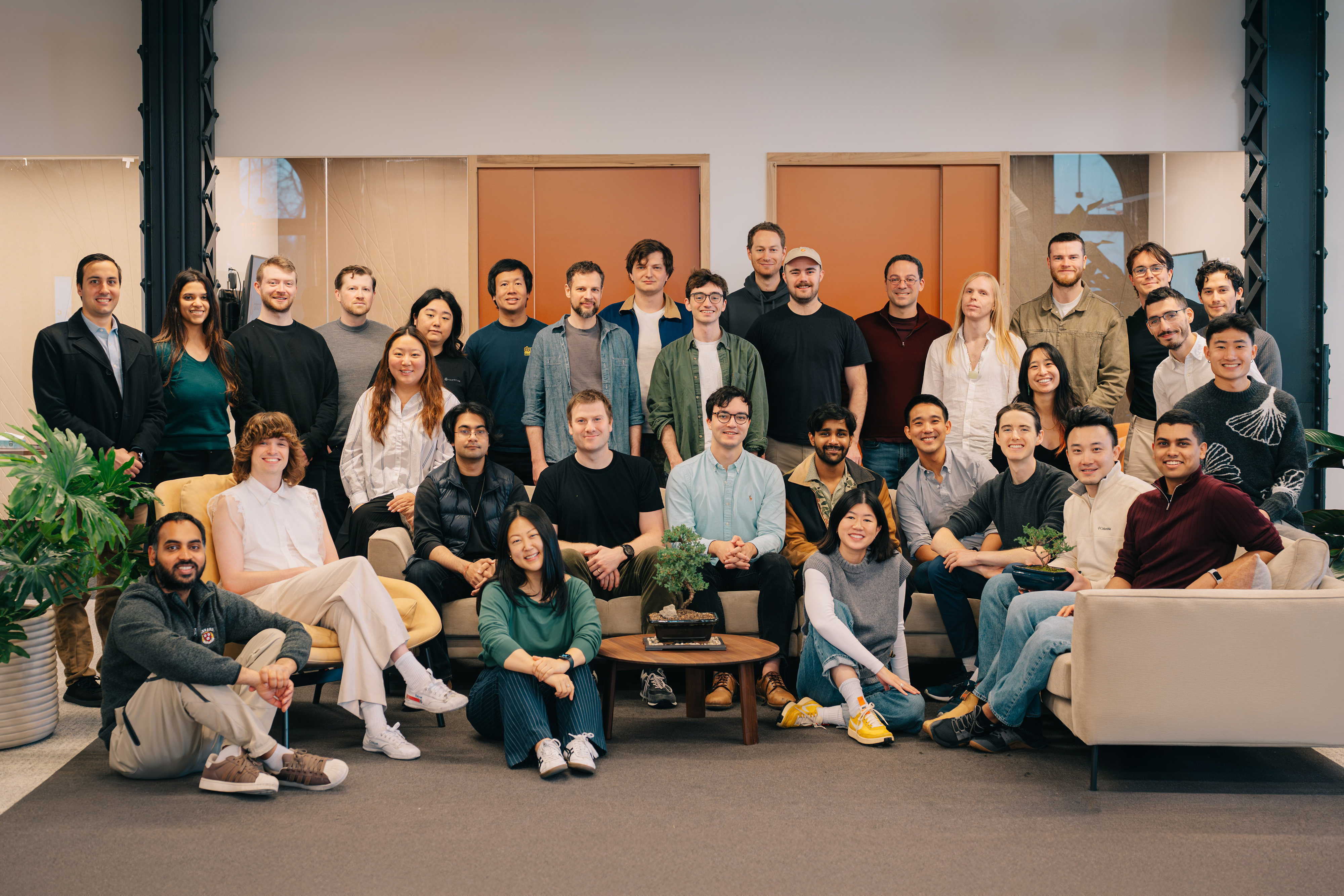 Eric Ho seated at the center of a group photograph with the Goodfire team in their office