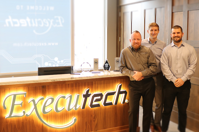 Eric Montague, Jeff Totten and Ramsey Sahyoun standing beside the Executech reception desk