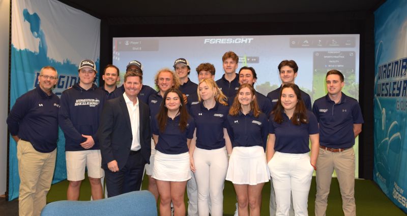 Eric Nyman standing with Virginia Wesleyan’s men’s and women’s golf teams in their new indoor practice center