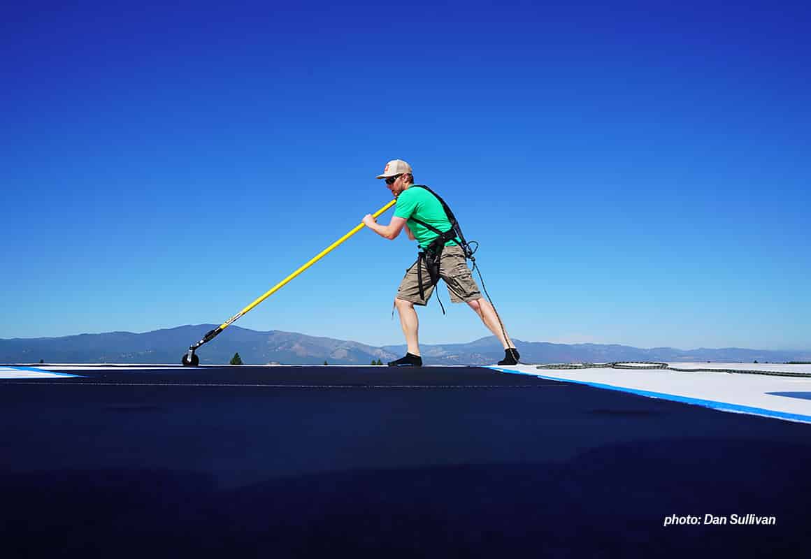 Eric Siegfried using a long-handled roller to paint an X on the onX office building