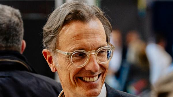 Eric Thord smiling, wearing clear-framed glasses and a dark jacket