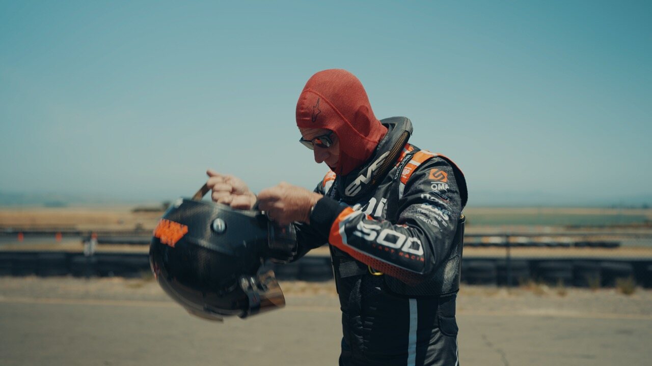Eric Verdin in racing gear, holding his helmet at the racetrack