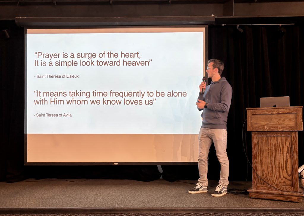 Erich Kerekes speaking beside a projected presentation about prayer