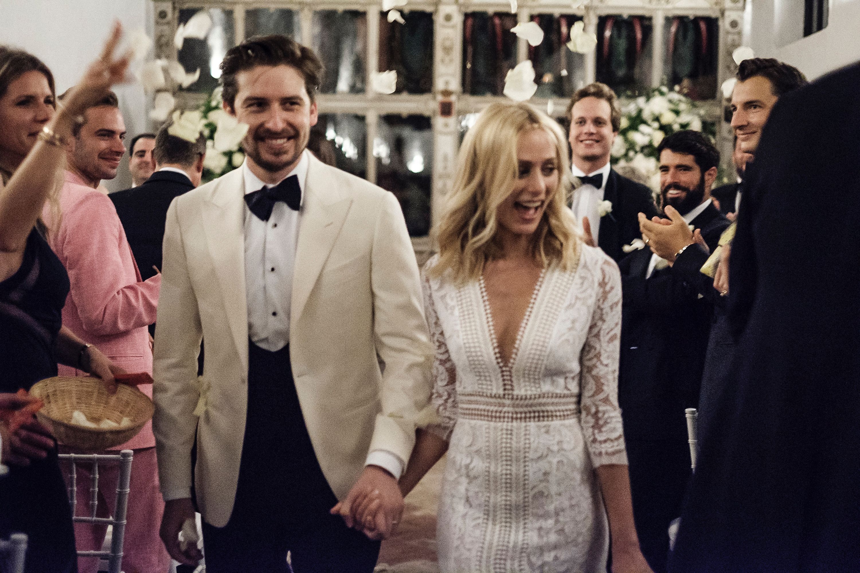 Erik Serrano Berntsen and Katherine Holmgren walk hand in hand at their wedding in Seville as guests throw petals.