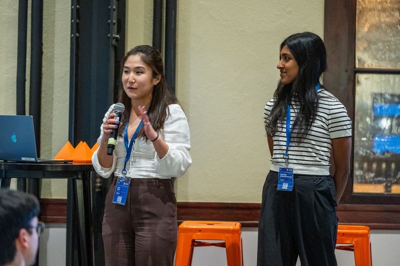 Erin Kim speaks with a microphone beside Mesh co-founder Nandini Ramakrishnan at an event