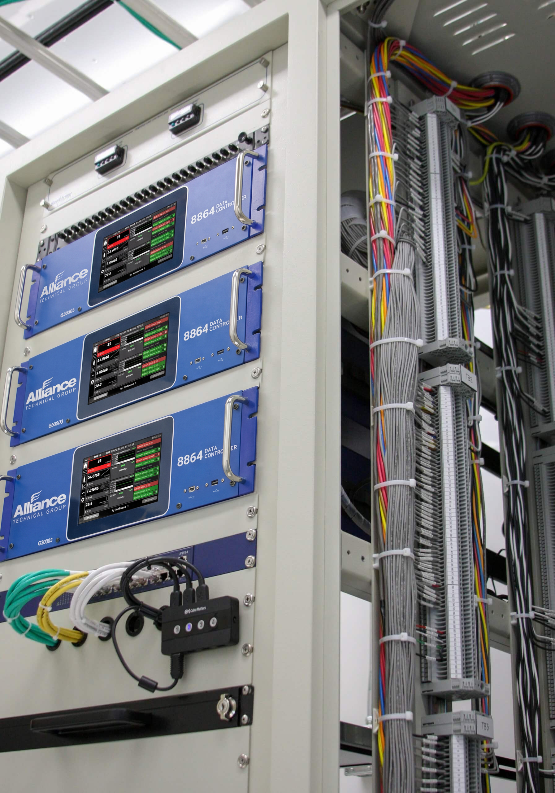 Three blue 8864 data controllers installed in an industrial rack beside organized wiring