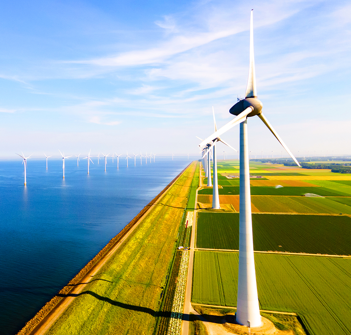 Wind turbines running along a coastal agricultural landscape