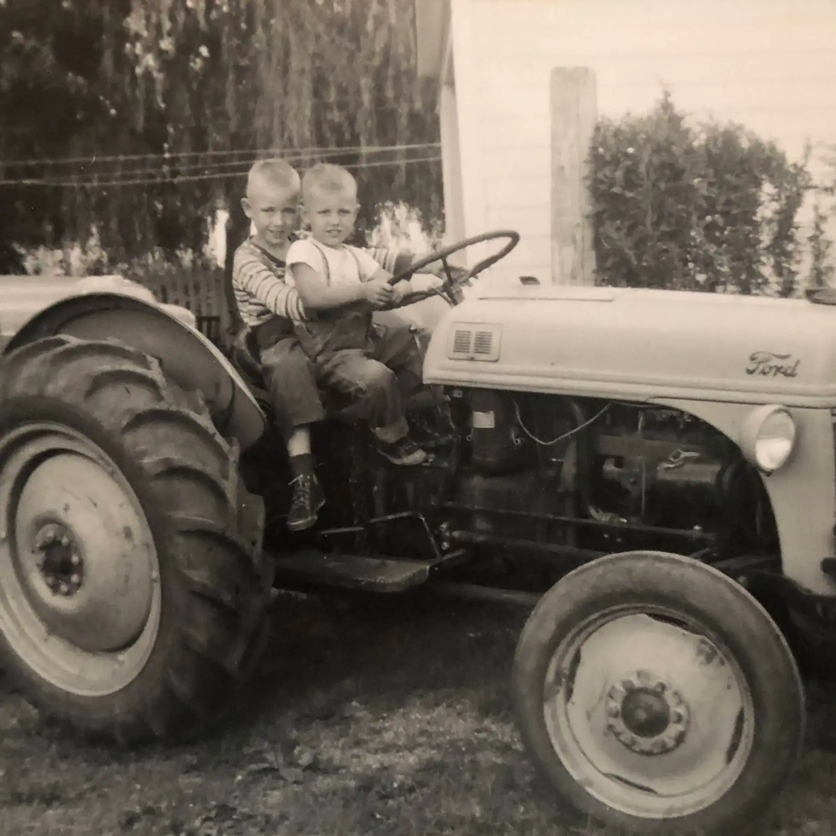 Jim and Essel Bailey as children sitting together on a Ford tractor