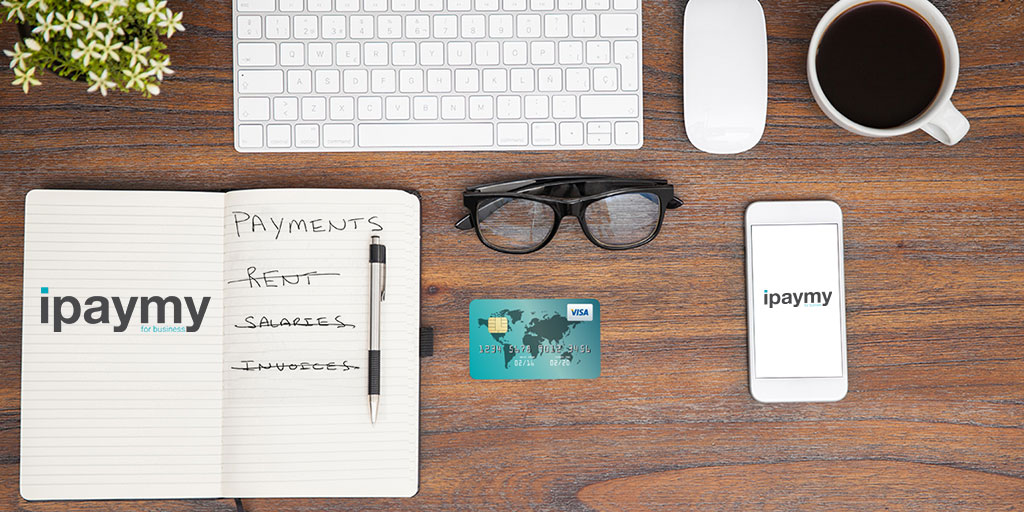 A 2017 ipaymy promotional desk scene with rent, salaries and invoices crossed off a notebook