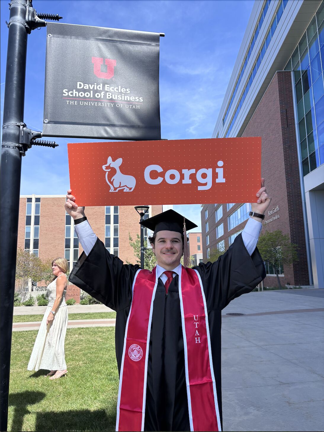 Ethan Noonan at University of Utah graduation holding a Corgi sign