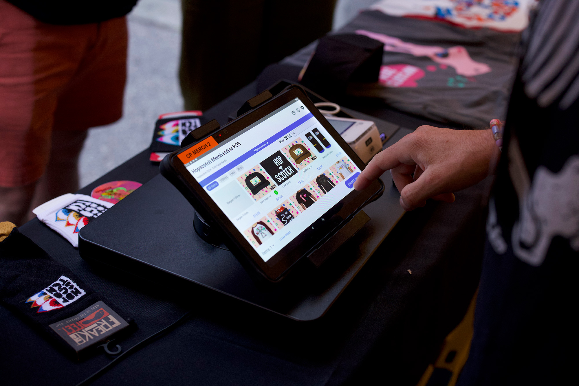 A seller uses Etix Octave on a tablet beside Hopscotch festival merchandise