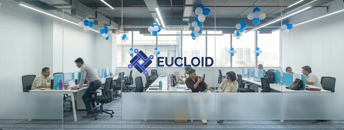 Employees at desks in Eucloid’s glass-fronted office, with blue and white balloons overhead