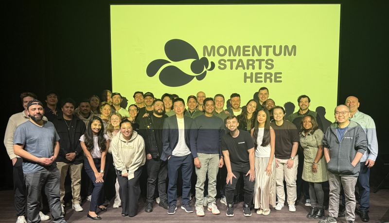 Members of the Franki team standing beneath a Momentum Starts Here sign at their 2026 kickoff