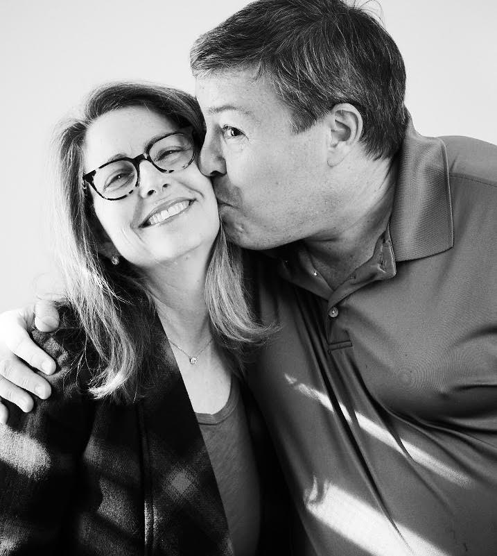 Eva Moskowitz smiling as her husband Eric Grannis kisses her cheek