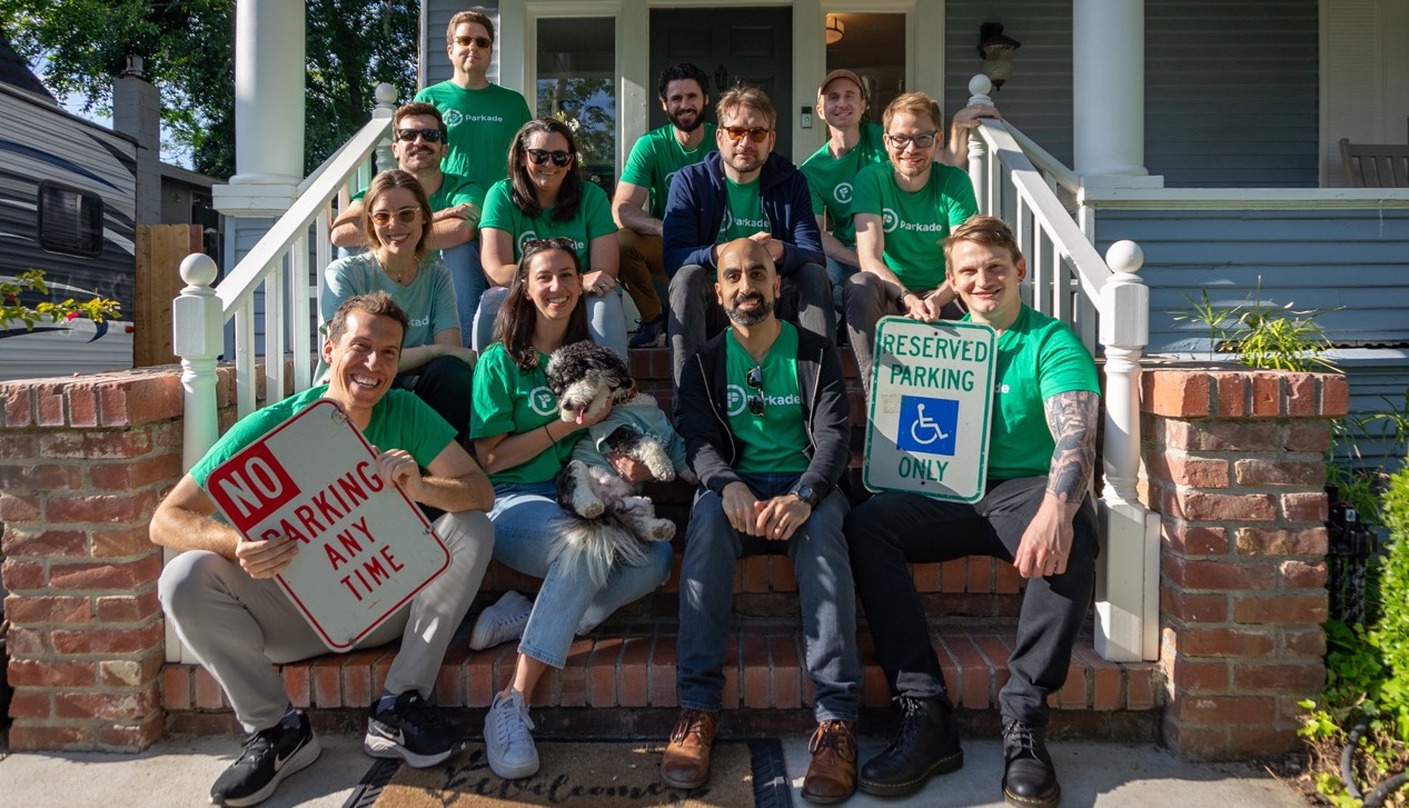 Evan Goldin at front left with the Parkade team on outdoor steps, holding parking signs