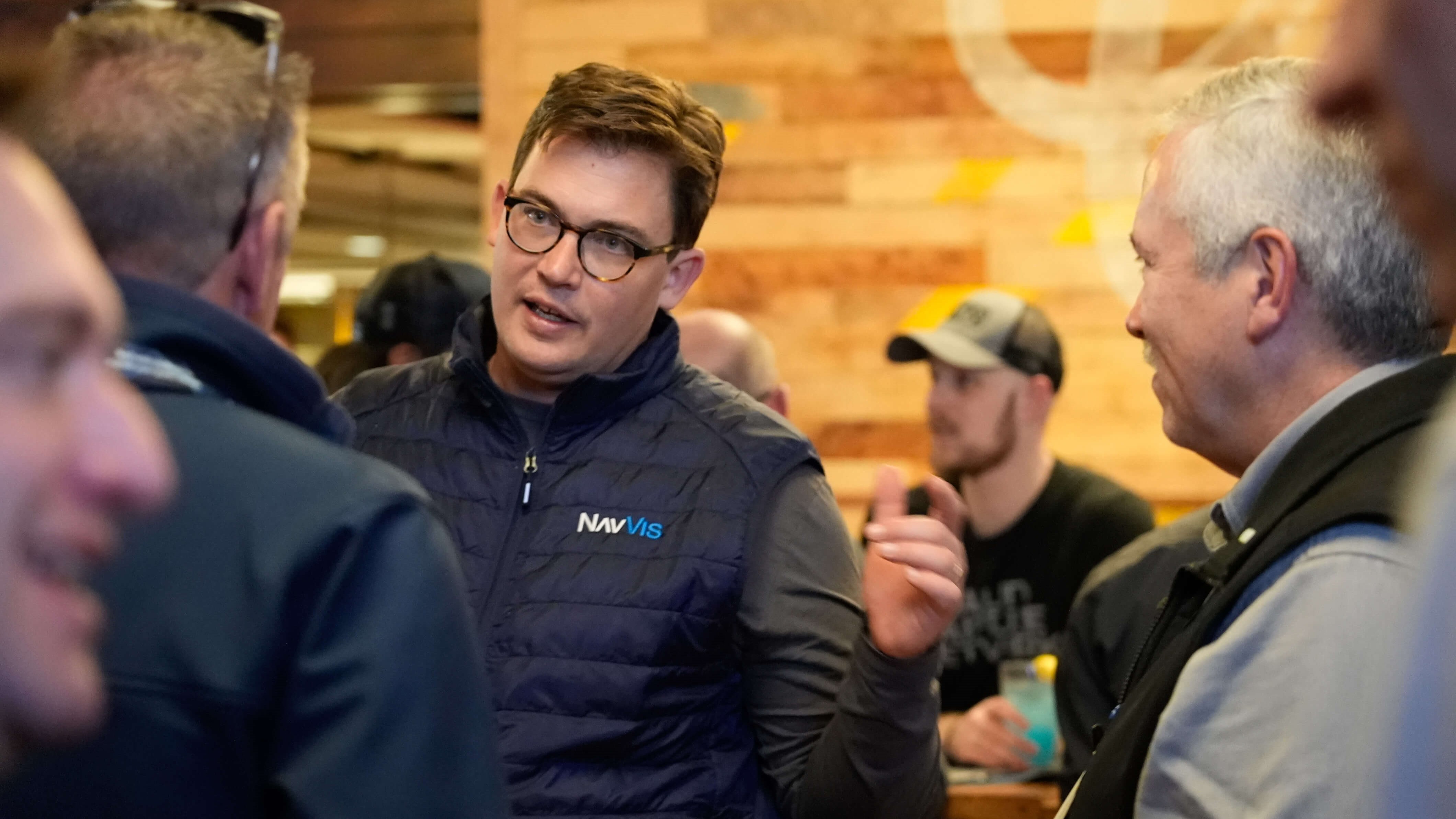 Evan McPhee in a NavVis vest speaking with attendees at an industry gathering