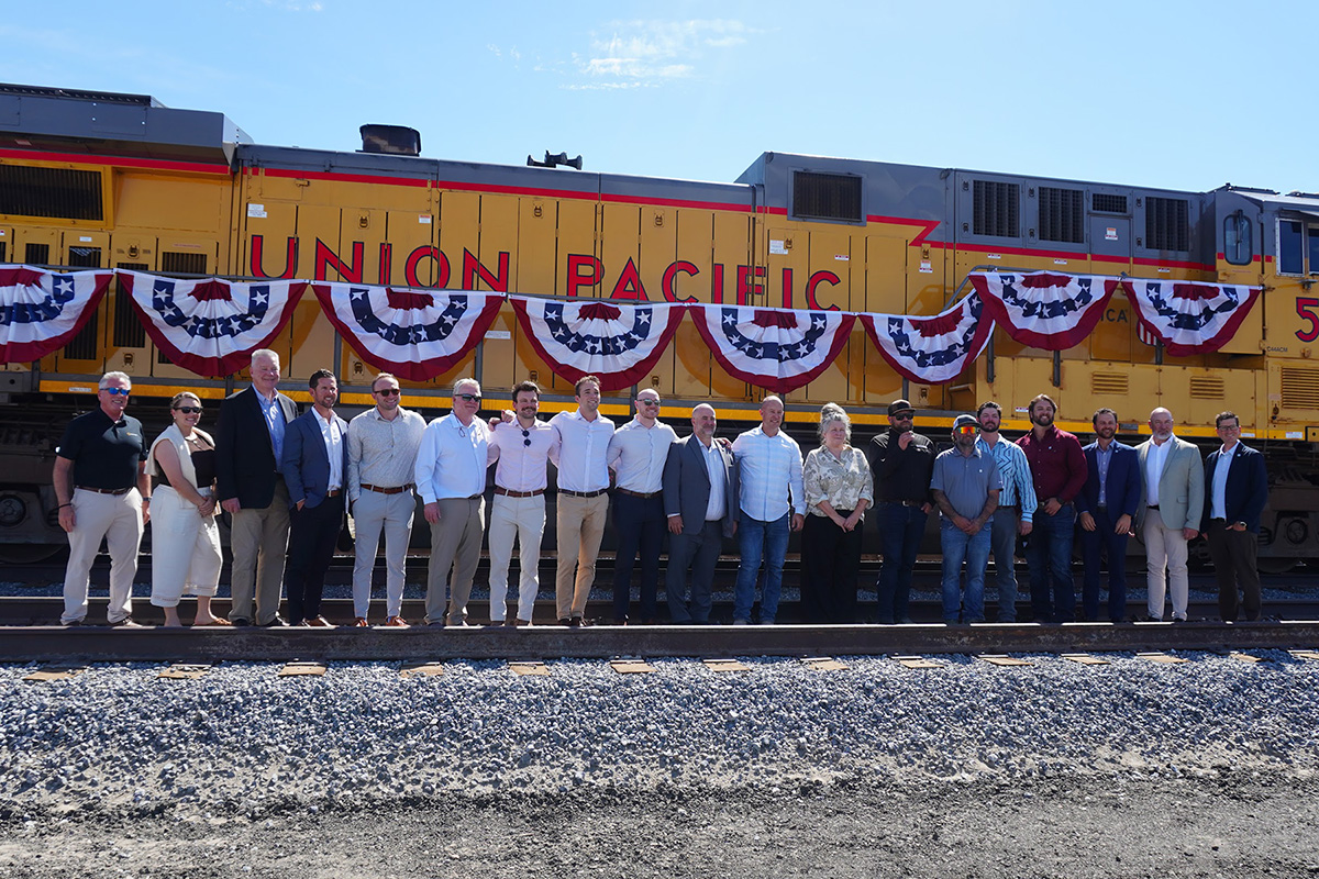 Officials and project participants standing beside a Union Pacific locomotive at Victory’s Silver Spike Ceremony