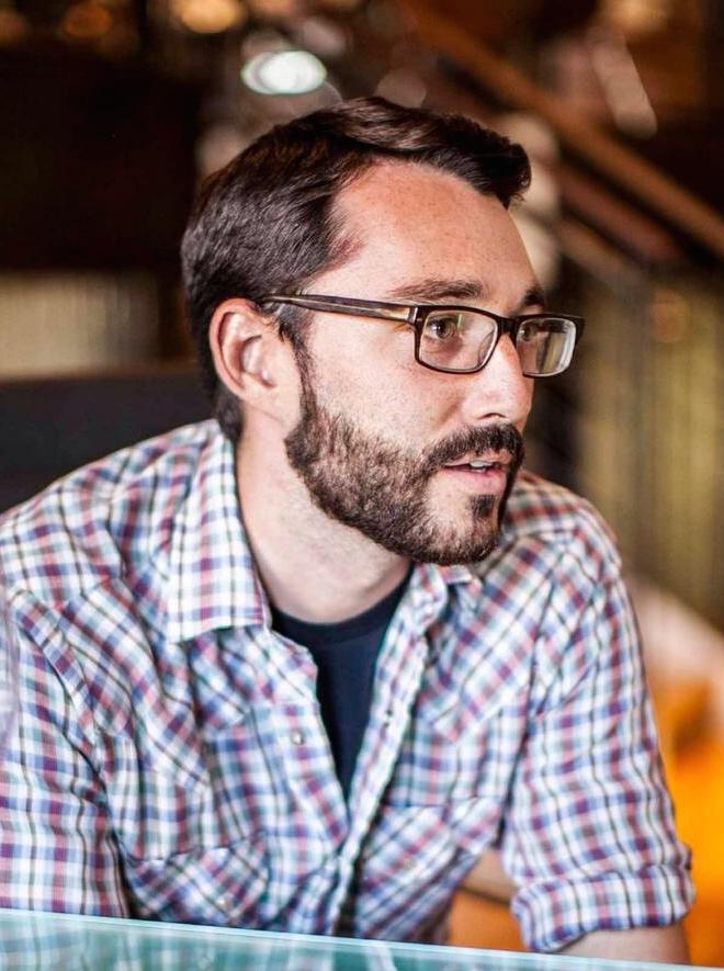 Evan Walden in conversation, wearing glasses and a plaid shirt