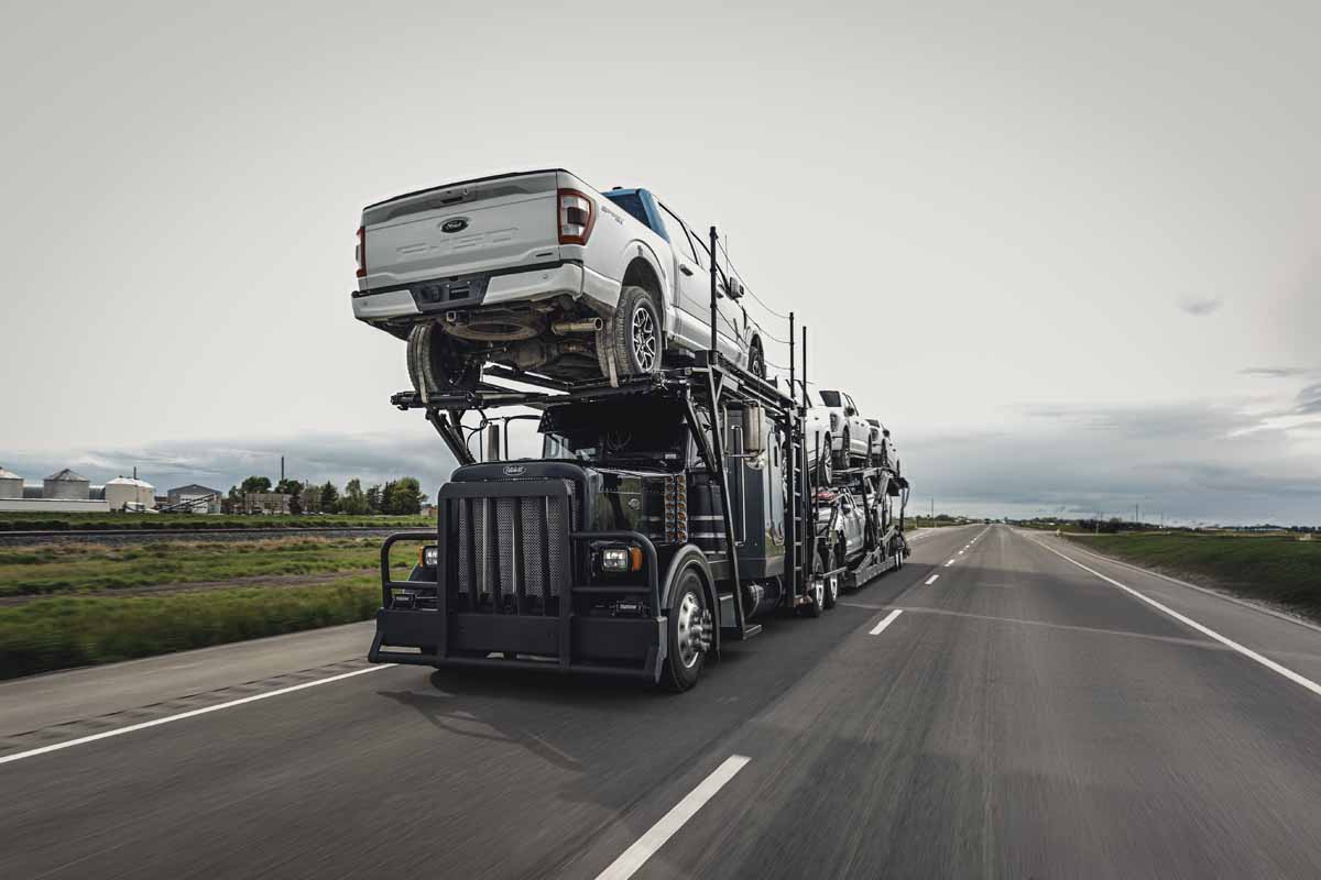 An Evans Trucking car carrier moving pickup trucks on a divided highway