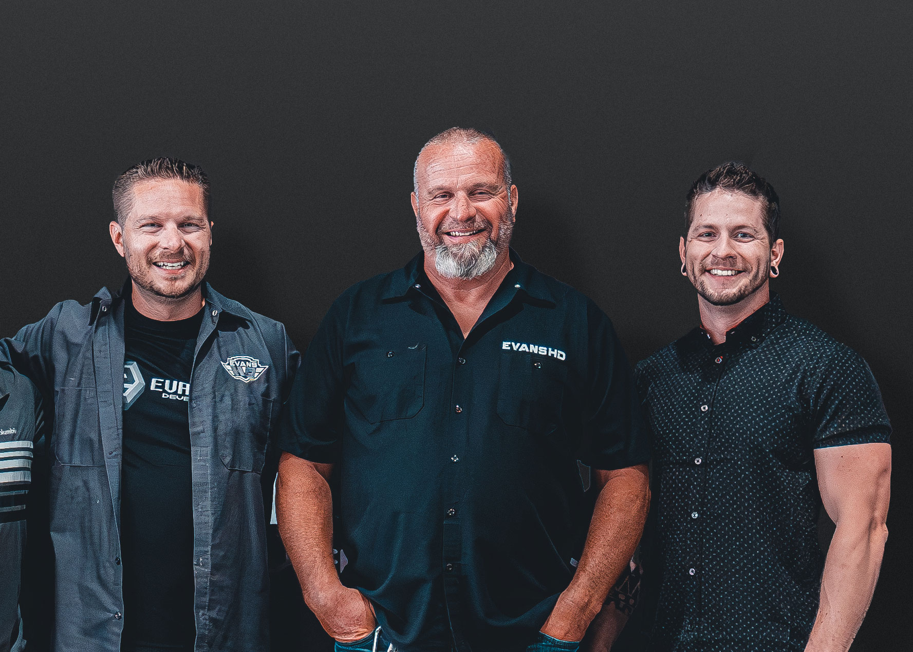 Jory, George and Reese Evans standing together against a dark background