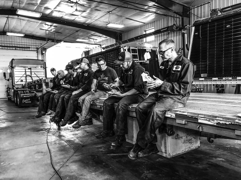 Evans maintenance crew sitting together on a trailer inside the repair shop